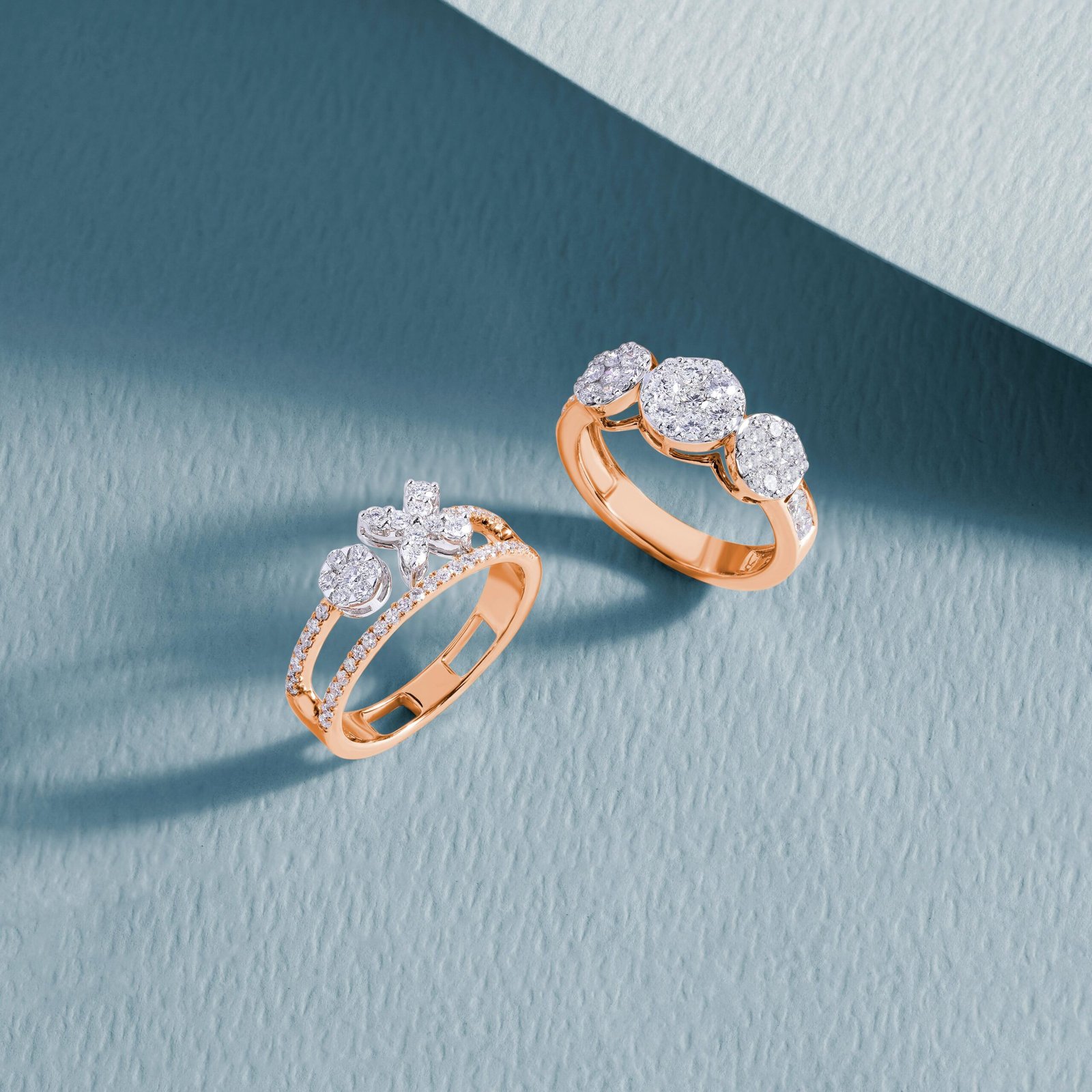 Close-up of luxurious diamond rings on a textured blue surface, showcasing elegance and craftsmanship.
