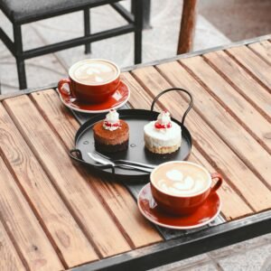 Warm ambient café in Kerman with cappuccinos and desserts served on a wooden table.