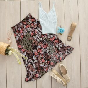 Boho-style outfit featuring floral skirt and accessories neatly arranged on a wooden floor.