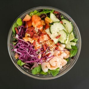 Fresh and colorful shrimp salad in a glass bowl featuring mixed vegetables and seeds.